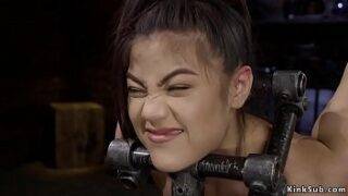 Brunette slave Kendra Spade with head locked and slightly bent forward in metal device bondage gets hot ass spanked then in other positions toyed