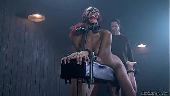 Redhead ebony slave Daisy Ducati in black latex outfit is bound on illuminating table then gets pussy zappered and ass spanked by master The Pope